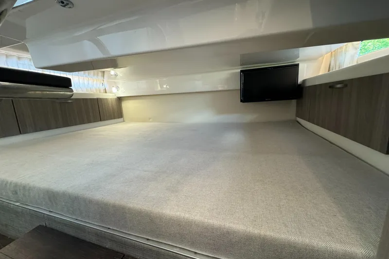 Mullin' It Over Again Yacht Photos Pics 2019 Regal 33 SAV cabin interior with bed and TV, featuring modern wood accents.