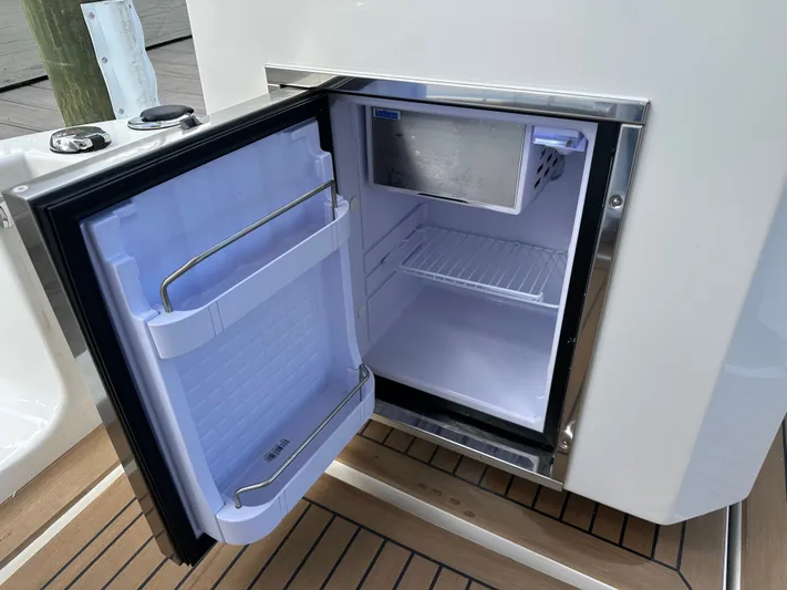  Yacht Photos Pics Open mini fridge on Aquila 36 Sport 2025 boat, showing interior shelves and freezer compartment.