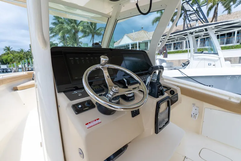 Innisfree Yacht Photos Pics 2015 Scout 300 LXF boat helm with steering wheel and controls, docked near palm trees.