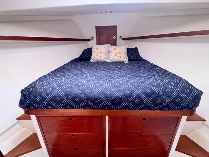 Veritas Yacht Photos Pics Cozy cabin interior of 2016 Wesmac 42 with blue bedding and wooden drawers.