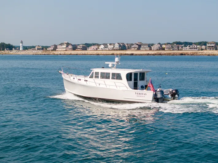 Veritas Yacht Photos Pics 2016 Wesmac 42 boat cruising near a coastal town with a lighthouse.