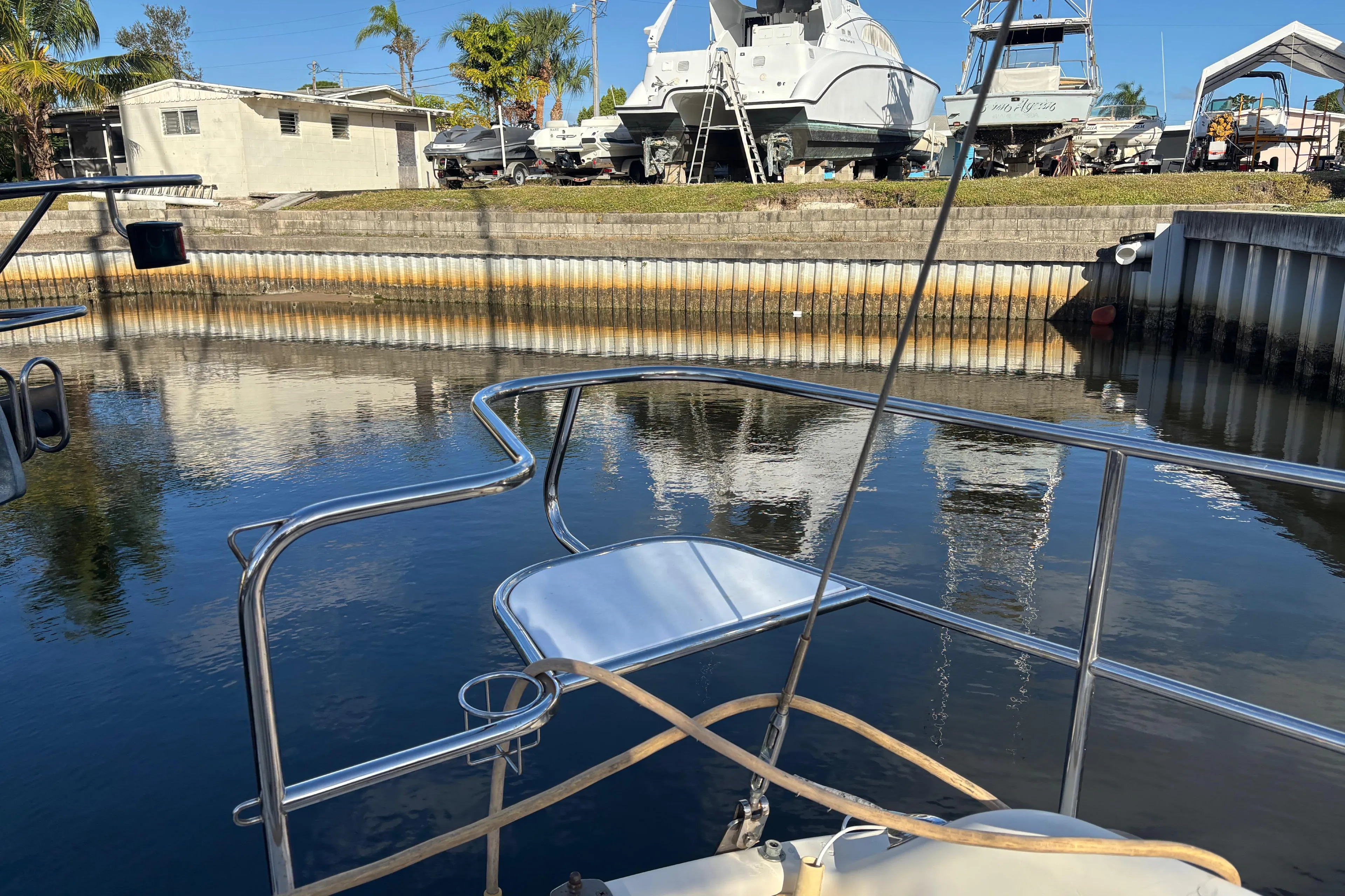 Bow of 1997 Caliber 40LRC yacht in a marina with boats and palm trees.