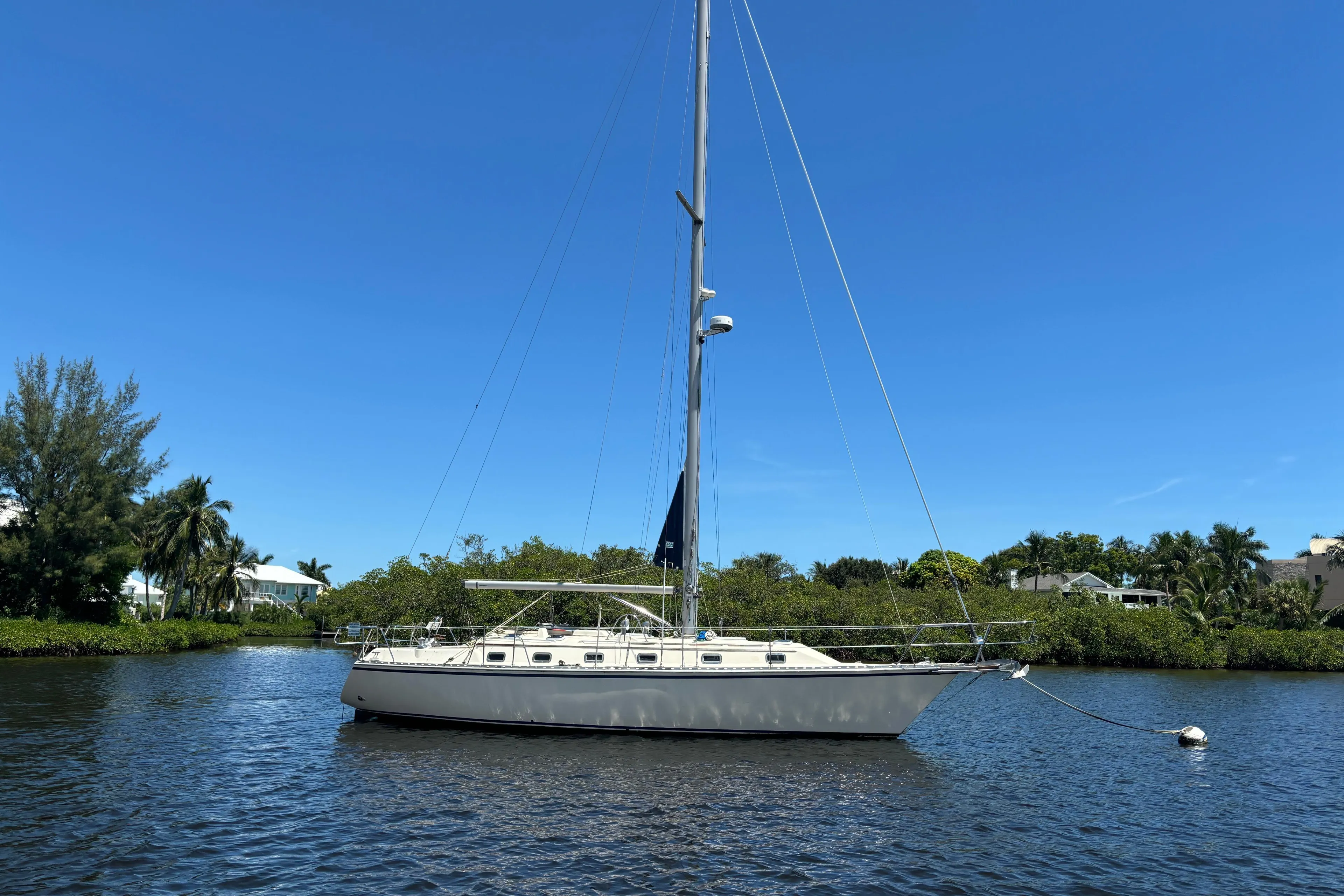 1997 Caliber 40LRC sailboat anchored on a calm river under a clear blue sky.