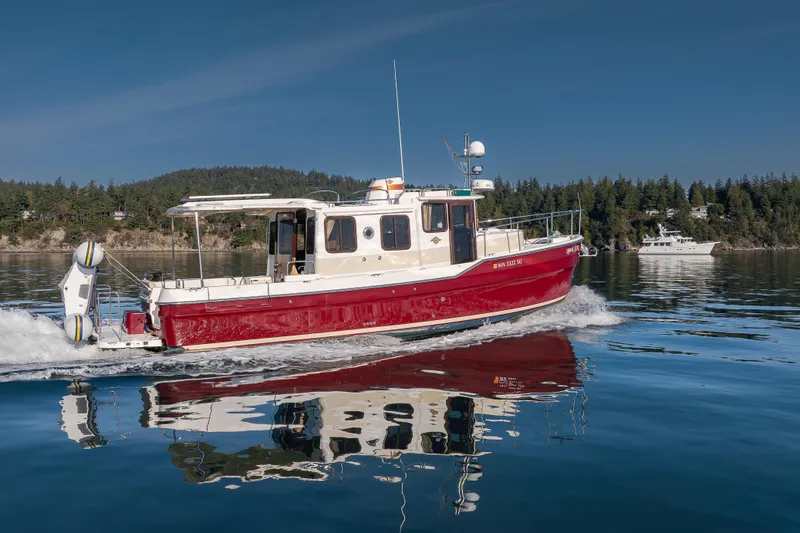 Lone Star Yacht Photos Pics 2022 Ranger Tugs R-31 S cruising on calm water with scenic forest backdrop.