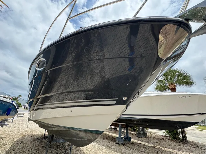  Yacht Photos Pics 2013 Monterey 320 Sport Yacht on display, sleek black hull, parked on gravel.