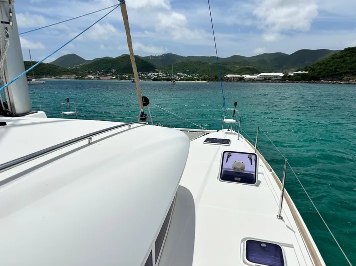  Yacht Photos Pics 2014 Lagoon 400 S2 catamaran sailing near lush green hills and turquoise waters.
