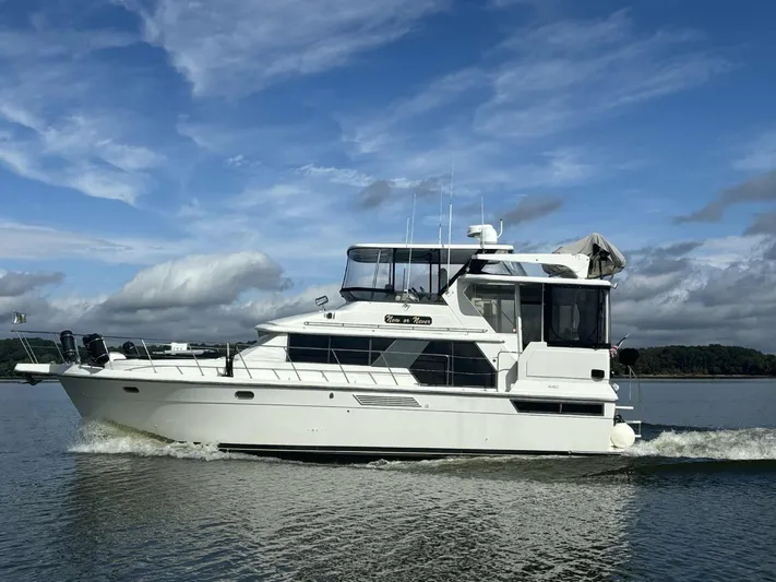 Now Or Never Yacht Photos Pics 1995 Carver 440 Aft Cabin Motor Yacht cruising on a calm lake under a blue sky.