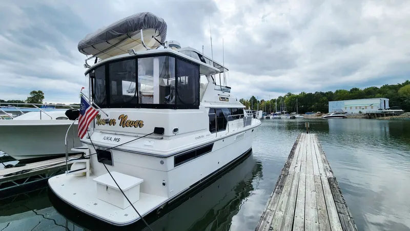 Now Or Never Yacht Photos Pics 1995 Carver 440 Aft Cabin Motor Yacht docked at marina under cloudy sky.