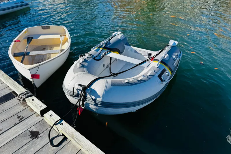 Walrus Yacht Photos Pics Two small boats docked on calm water near a wooden pier.