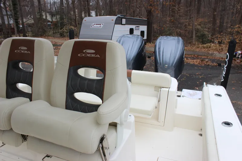  Yacht Photos Pics 2022 Cobia 280 Center Console boat seats with dual outboard motors in wooded area.