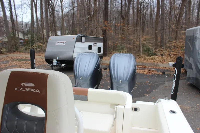  Yacht Photos Pics 2022 Cobia 280 Center Console boat with dual engines, parked near a forested area.