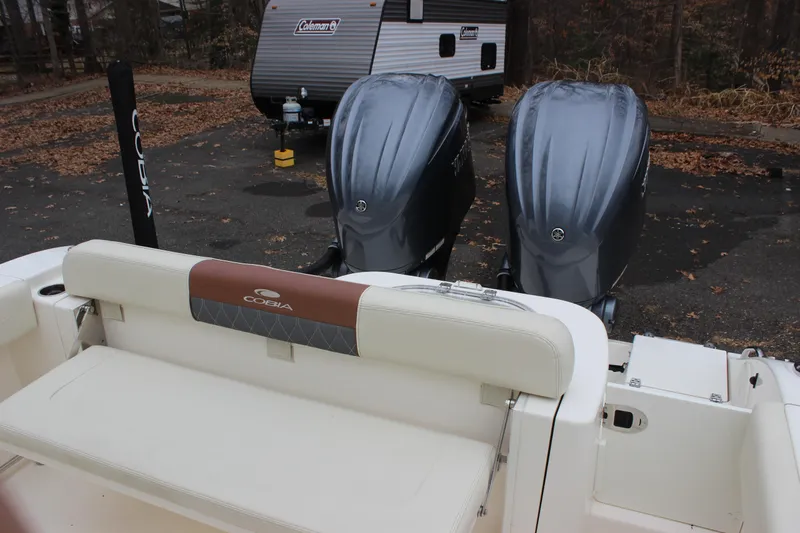  Yacht Photos Pics 2022 Cobia 280 Center Console boat with dual outboard engines in a parking area.
