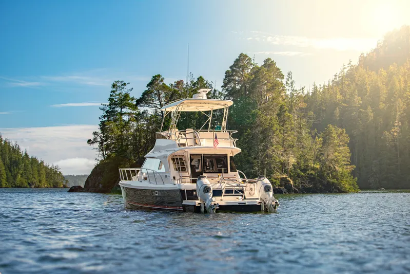 Yacht Photos Pics Aspen C128 Flybridge 2026 yacht cruising in scenic forested waterway under sunny skies.