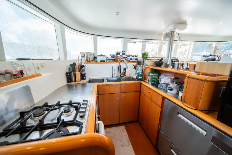  Yacht Photos Pics Modern kitchen interior on a 2007 Lagoon 500 yacht, featuring wooden cabinetry and stainless steel appliances.