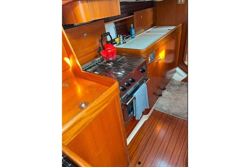  Yacht Photos Pics Interior of 1995 Beneteau Oceanis 44 CC yacht kitchen with stove and wooden cabinetry.