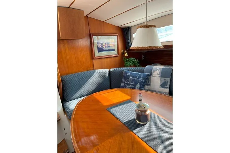  Yacht Photos Pics Cozy interior of 1995 Beneteau Oceanis 44 CC sailboat with wooden table and nautical decor.