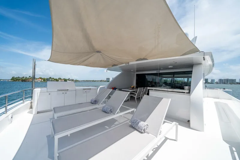 Day One Yacht Photos Pics Luxurious 2020 Hargrave C92 yacht deck with sun loungers and canopy, overlooking serene waters.