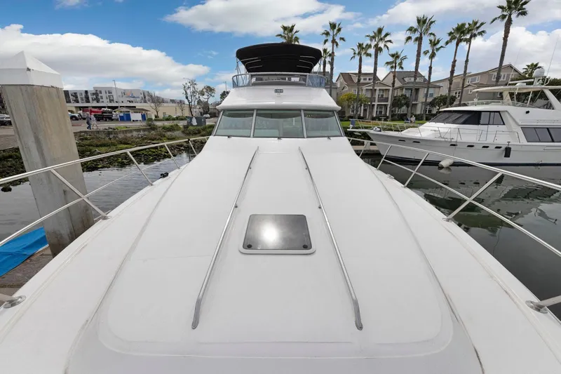  Yacht Photos Pics 1994 Sea Ray 550 Sedan Bridge yacht docked, with palm trees and buildings in the background.