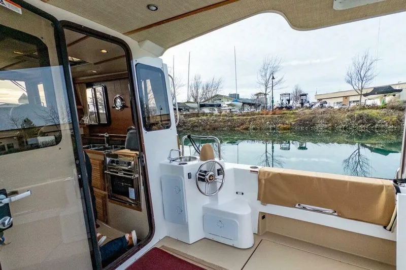 R & R Yacht Photos Pics 2019 Ranger Tugs R-31-S boat interior with kitchen and helm, docked by calm water.