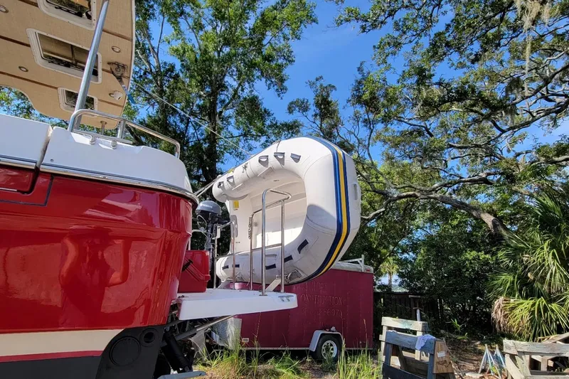 R & R Yacht Photos Pics 2019 Ranger Tugs R-31-S with inflatable boat, parked outdoors under trees.