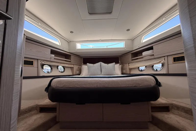 Electric Summer Yacht Photos Pics Luxurious cabin interior of 2024 Greenline 48 Fly Hybrid yacht, featuring elegant bedding and porthole windows.