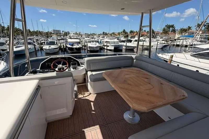 Electric Summer Yacht Photos Pics 2024 Greenline 48 Fly Hybrid yacht interior with marina view, featuring elegant seating and wooden table.