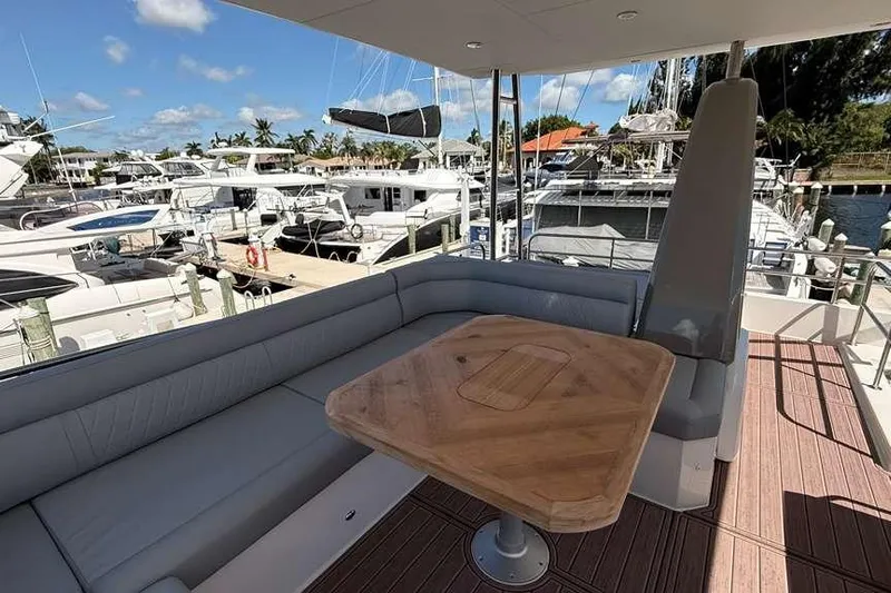 Electric Summer Yacht Photos Pics 2024 Greenline 48 Fly Hybrid yacht deck with seating and wooden table, docked at marina.