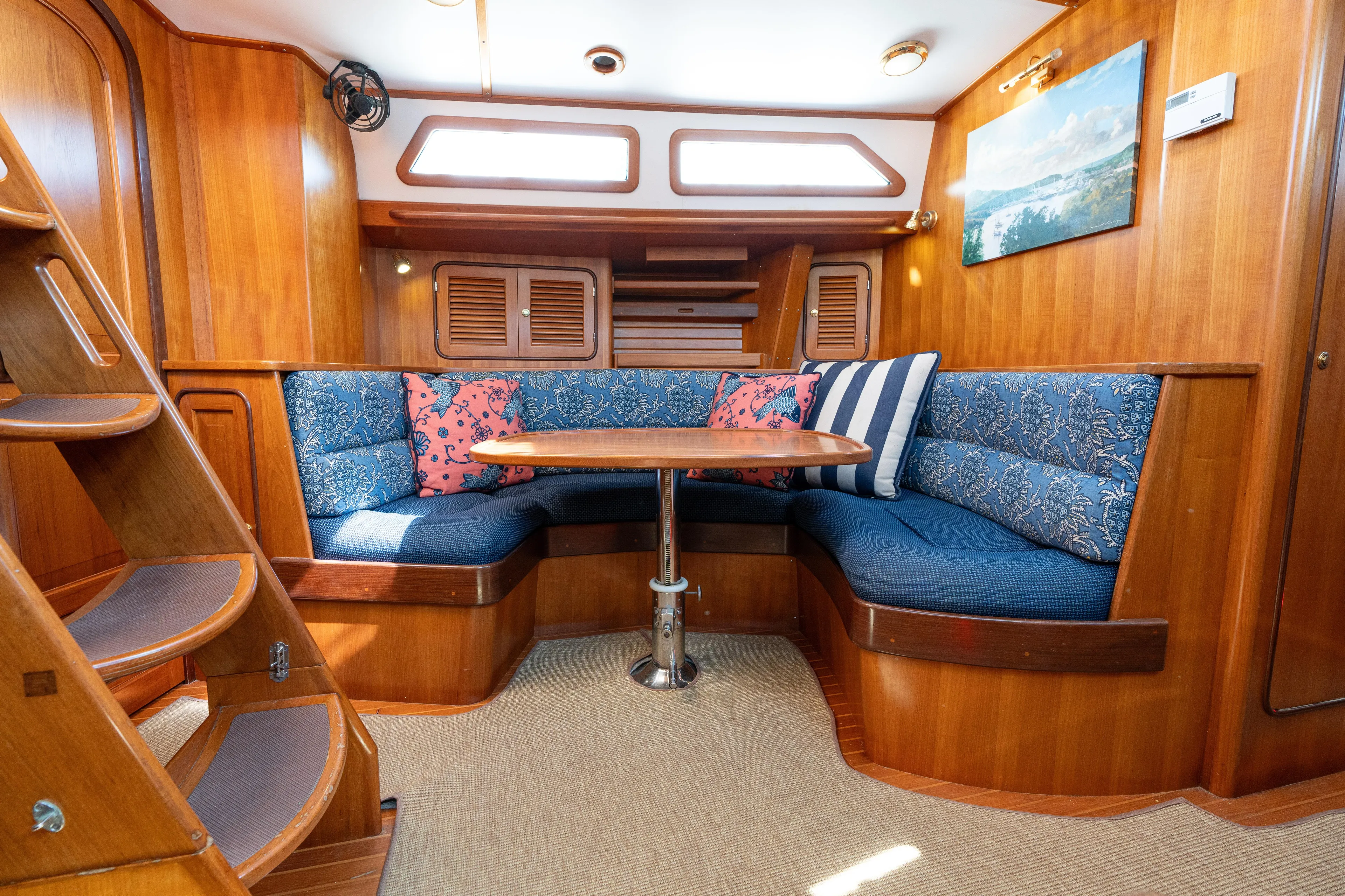 Altair Yacht Photos Pics Cozy interior of 2002 Passport 470 Center Cockpit Ketch with blue seating and wooden finishes.