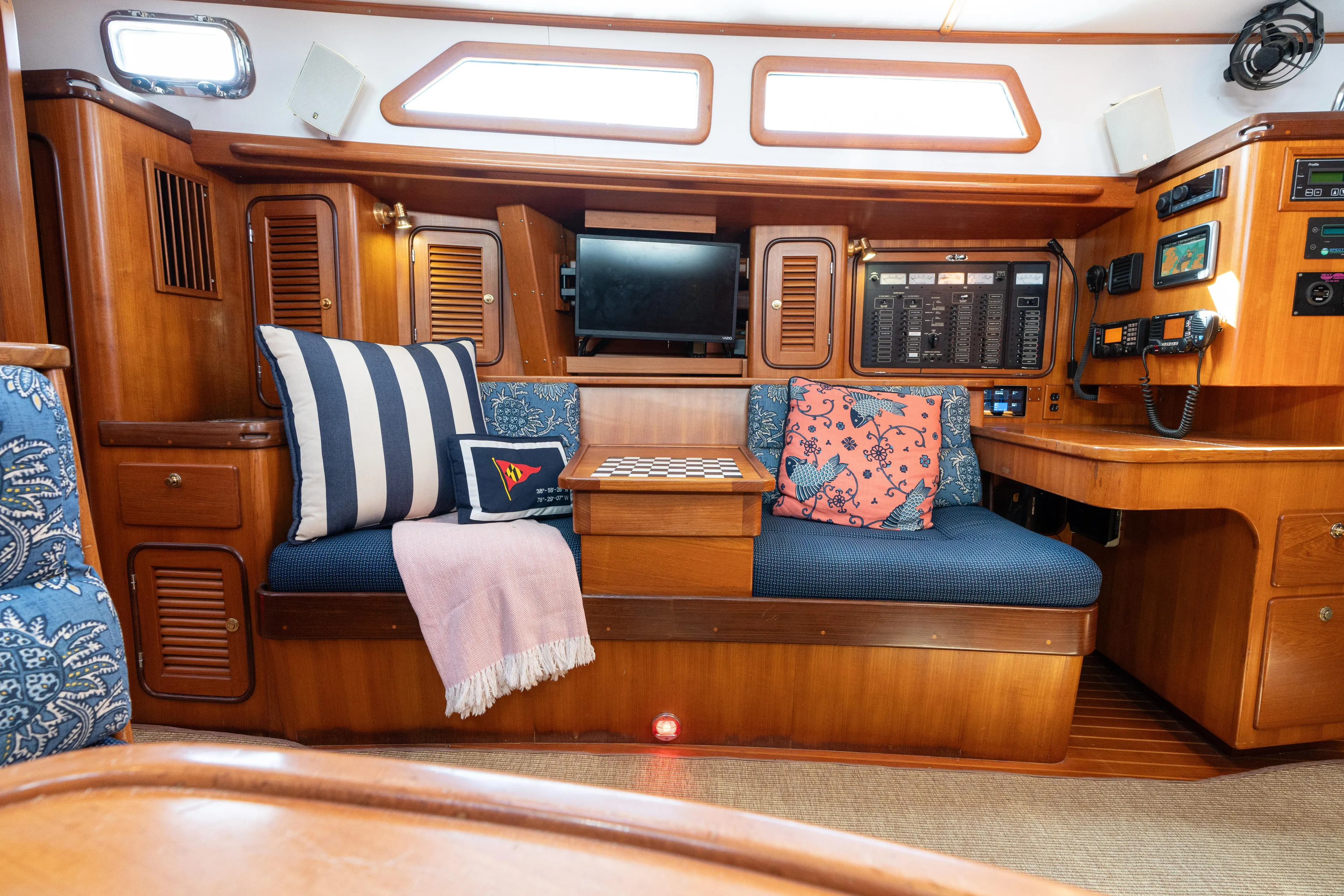 Altair Yacht Photos Pics Cozy interior of 2002 Passport 470 Center Cockpit Ketch with seating, pillows, and control panel.