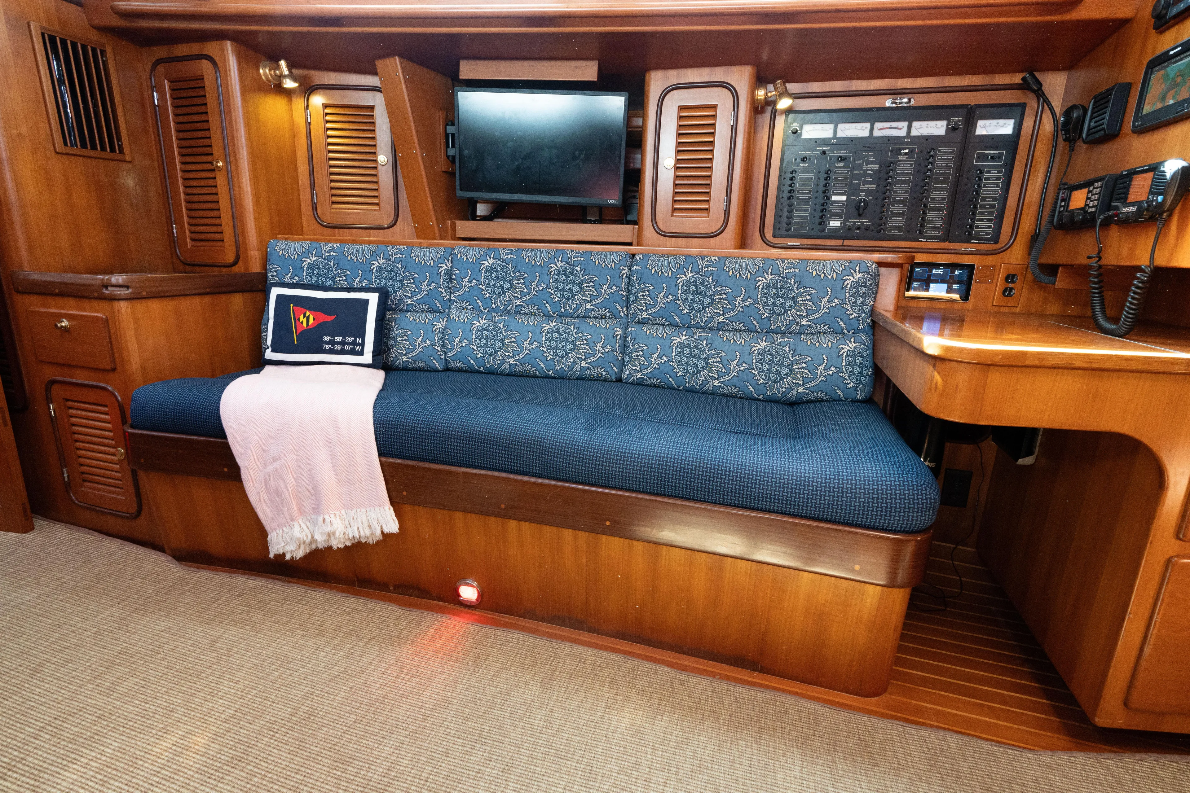 Altair Yacht Photos Pics Interior of 2002 Passport 470 Center Cockpit Ketch with blue cushioned seating and control panel.