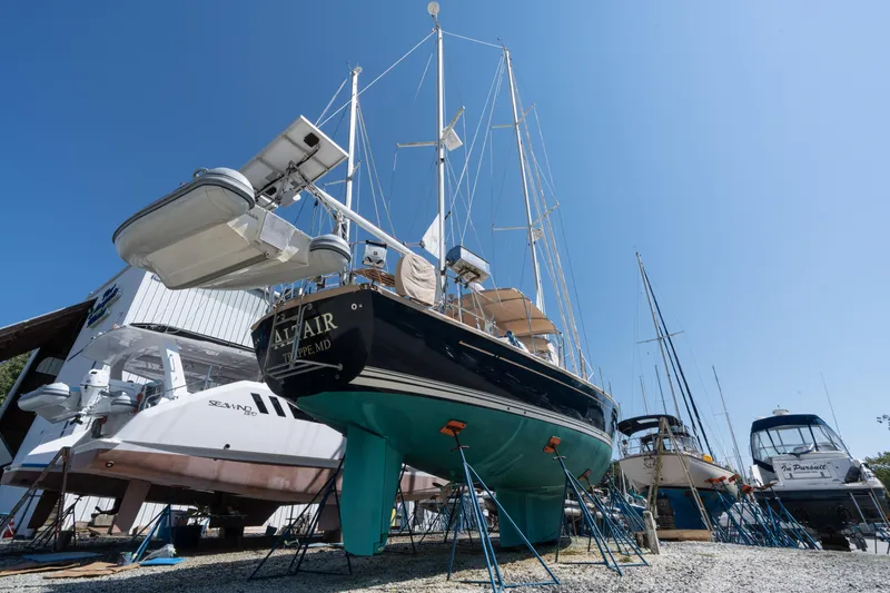 Altair Yacht Photos Pics Passport 470 Center Cockpit Ketch 2002 sailboat on stands in a boatyard under clear blue sky.