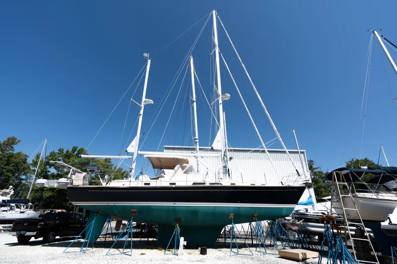 Altair Yacht Photos Pics Passport 470 Center Cockpit Ketch, 2002 model, on stands in a boatyard under clear blue sky.