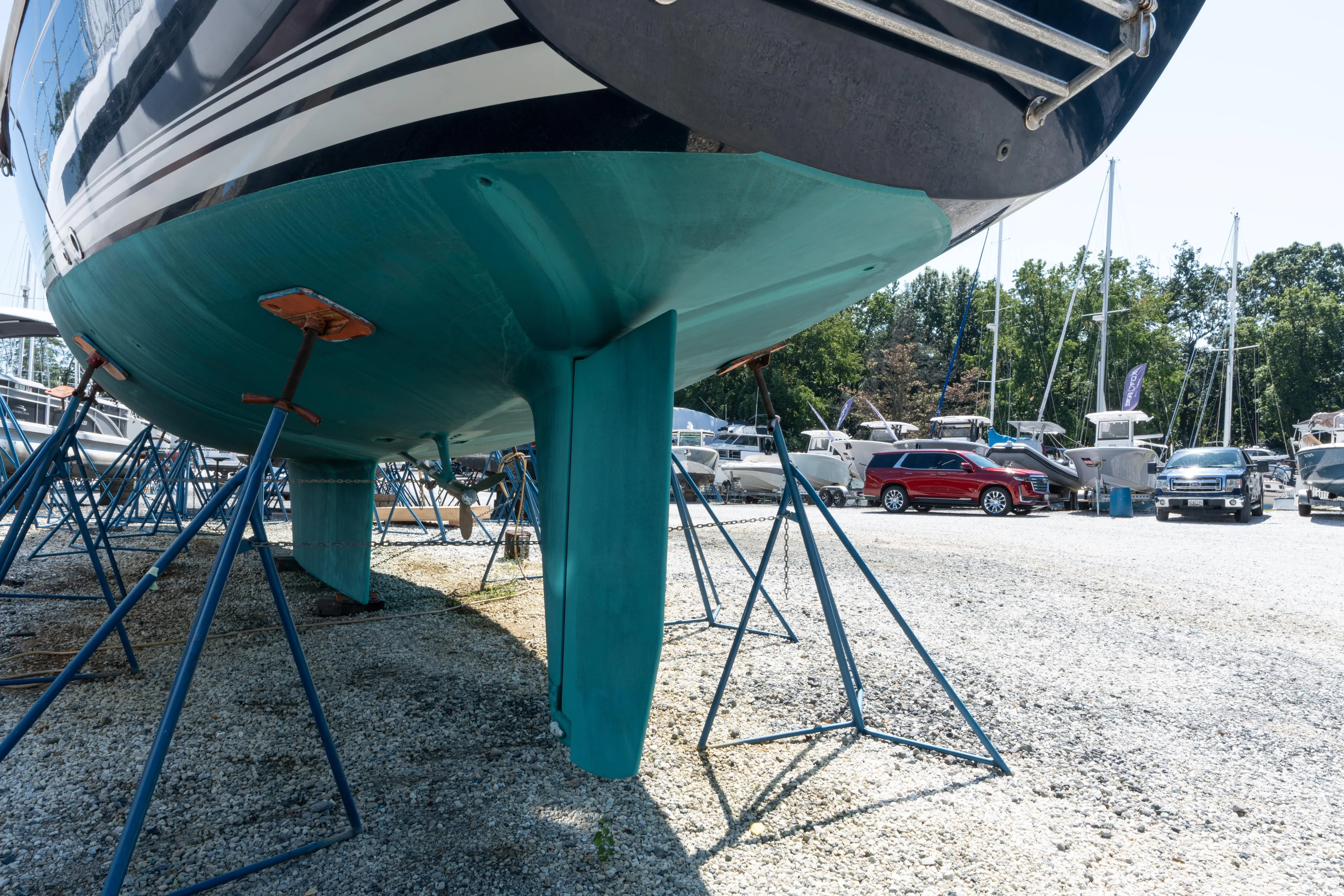 Altair Yacht Photos Pics Passport 470 Center Cockpit Ketch 2002 on stands in a boatyard, surrounded by vehicles.