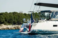 Luxury CNB 66 yacht sailing near a forested coastline, 2021 model.