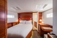 Luxurious cabin interior of 2021 CNB 66 yacht with wooden finishes and cozy bed.