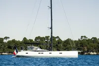 Sleek 2021 CNB 66 yacht sailing near a forested coastline.