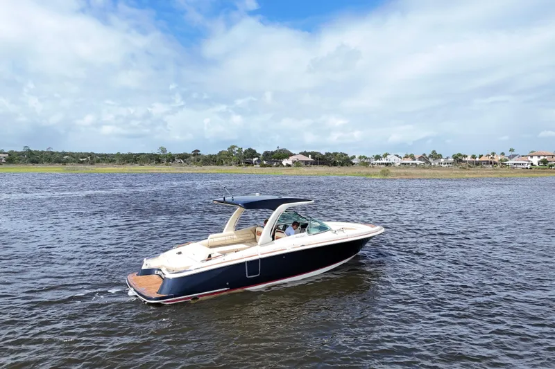  Yacht Photos Pics 2020 Chris-Craft Launch 31 GT boat cruising on a scenic lake under a partly cloudy sky.