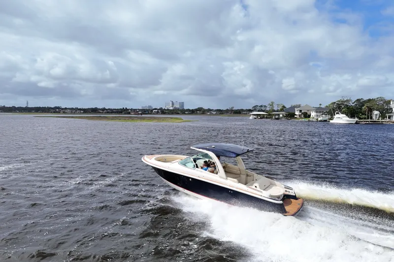  Yacht Photos Pics 2020 Chris-Craft Launch 31 GT cruising on a scenic waterway under a cloudy sky.