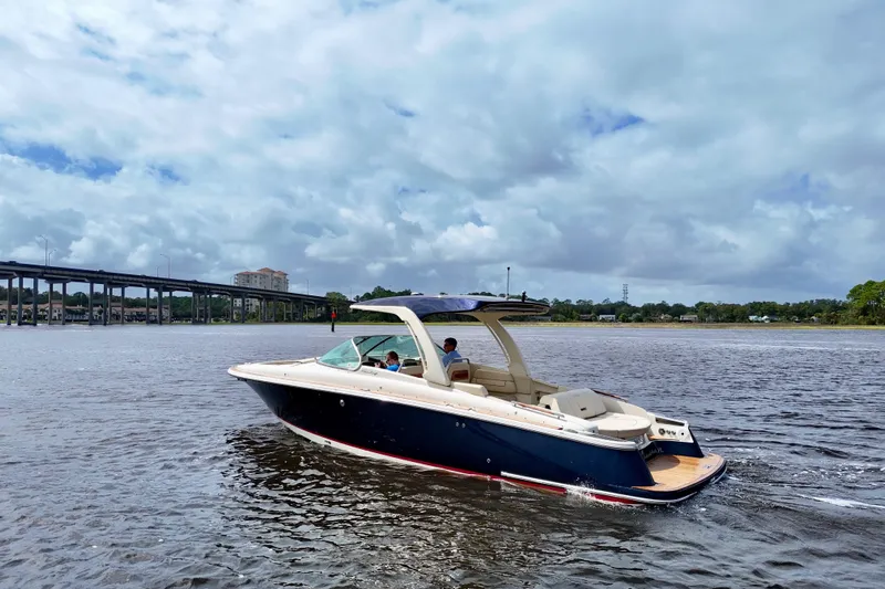  Yacht Photos Pics 2020 Chris-Craft Launch 31 GT boat cruising on a scenic river under a cloudy sky.
