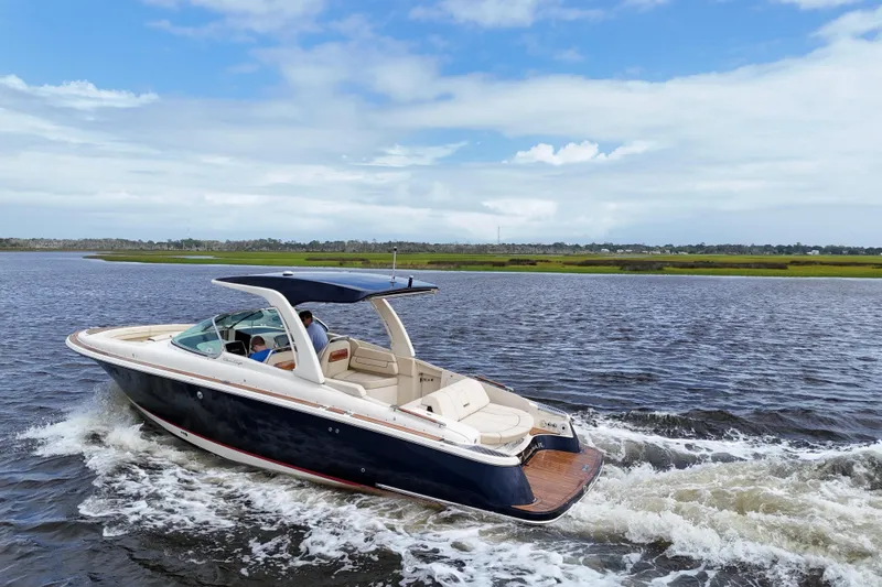  Yacht Photos Pics 2020 Chris-Craft Launch 31 GT cruising on a scenic waterway under a blue sky.