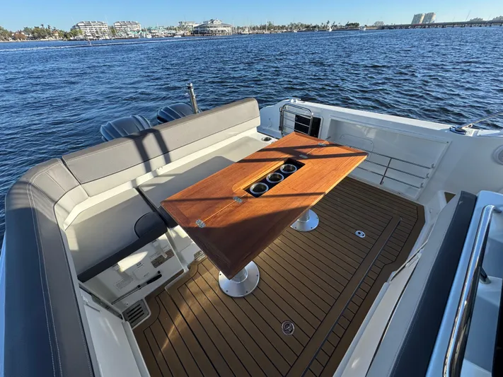 Make It Happen Yacht Photos Pics Jeanneau Leader 9.0 WA 2022 boat interior with wooden table and seating, overlooking water.