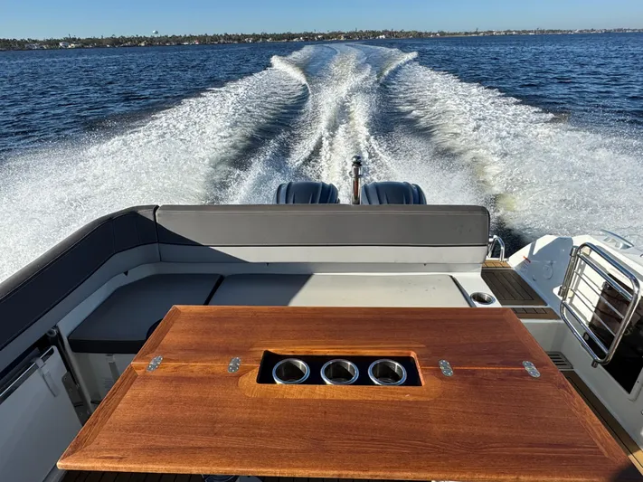 Make It Happen Yacht Photos Pics 2022 Jeanneau Leader 9.0 WA cruising on open water, view from deck with wooden table.