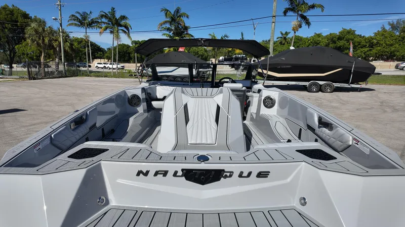  Yacht Photos Pics 2026 Nautique Ski boat interior with sleek design, parked outdoors under clear blue sky.