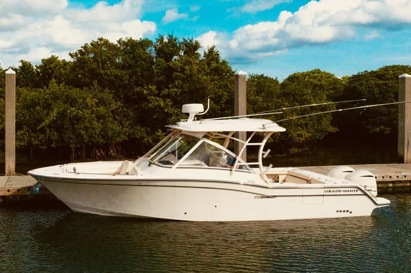 Sweet Life Yacht Photos Pics 2019 Grady-White Freedom 325 boat docked by lush greenery under blue sky.