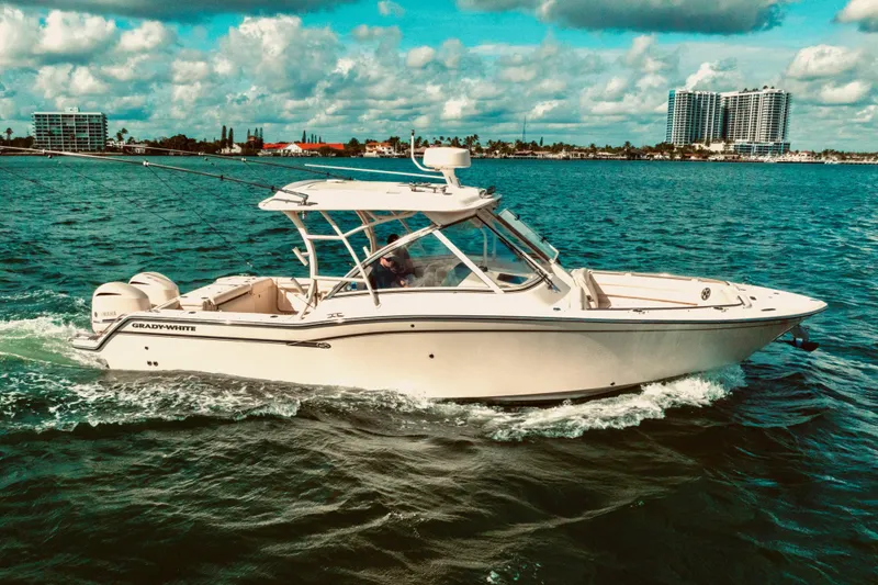 Sweet Life Yacht Photos Pics 2019 Grady-White Freedom 325 boat cruising on blue ocean near city skyline.