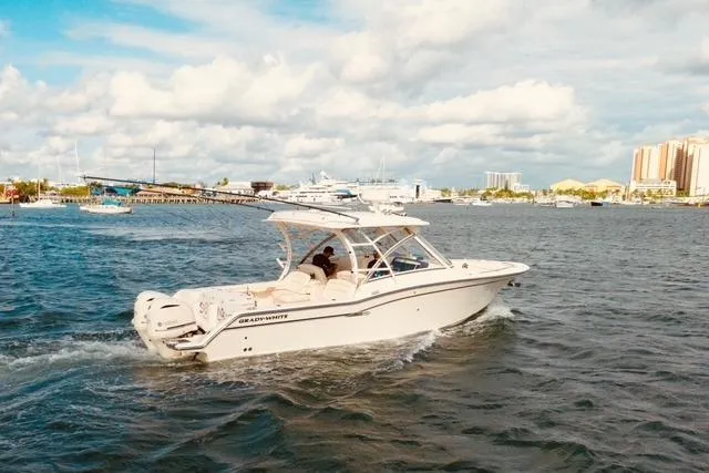 Sweet Life Yacht Photos Pics 2019 Grady-White Freedom 325 boat cruising on a sunny day near a city skyline.