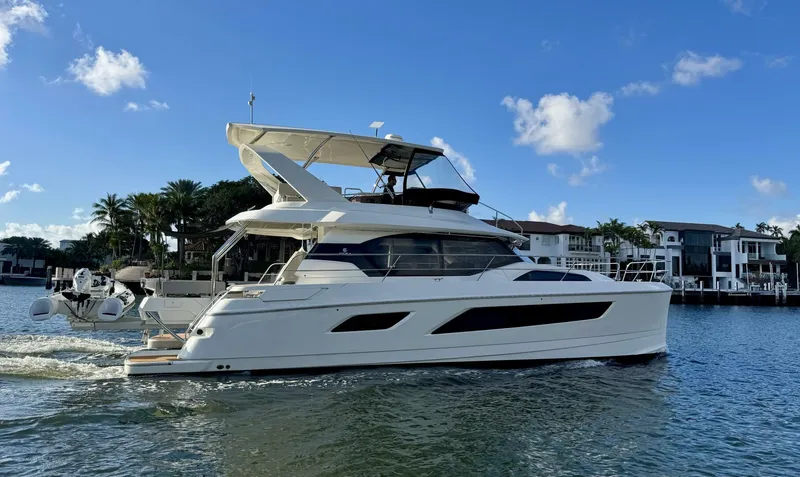 Roosterfish Yacht Photos Pics 2022 Aquila 44 yacht cruising on a sunny day near waterfront homes.