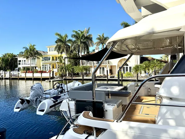Roosterfish Yacht Photos Pics Aquila 44 yacht docked by waterfront homes, 2022 model, sunny day, palm trees in background.