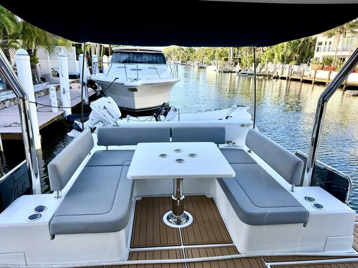 Roosterfish Yacht Photos Pics Aquila 44 yacht interior with seating and table, docked by a serene waterfront.
