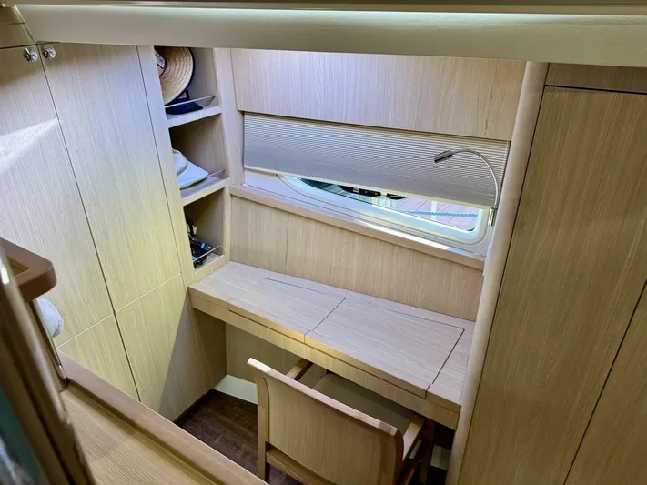 Roosterfish Yacht Photos Pics 2022 Aquila 44 yacht interior with wooden desk, chair, and shelves.